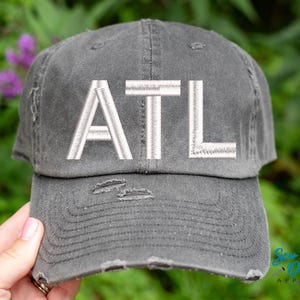 May include: A gray distressed baseball cap with white embroidered text that reads "ATL".