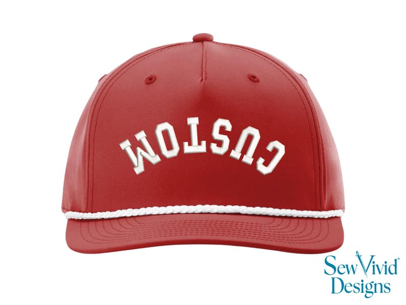 Puede incluir: Gorra de b&eacute;isbol roja con la palabra "CUSTOM" bordada en blanco, arqueada en la parte delantera. La gorra tiene un detalle de cuerda blanca a lo largo del borde y un peque&ntilde;o bot&oacute;n en la parte superior. El logotipo de Sew Vivid Designs est&aacute; en la esquina inferior derecha.
