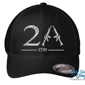 Peut inclure: Casquette de baseball noire avec un motif brodé blanc représentant le chiffre "2A" avec deux fusils croisés en dessous et le texte "1791".