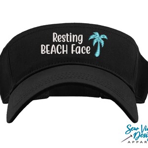 May include: Black visor with white embroidery that reads "Resting Beach Face" and a blue palm tree graphic.