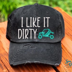 May include: Black distressed baseball cap with white embroidery that reads "I like it dirty" and a turquoise silhouette of an off-road vehicle.