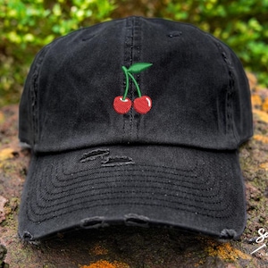 May include: A black distressed baseball cap with a red cherry embroidered on the front.