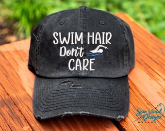 May include: Black distressed baseball cap with white embroidery that reads "Swim Hair Don't Care" and a blue silhouette of a swimmer.
