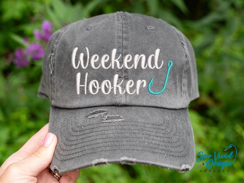 May include: A gray distressed baseball cap with the text "Weekend Hooker" embroidered in white with a turquoise fishing hook.