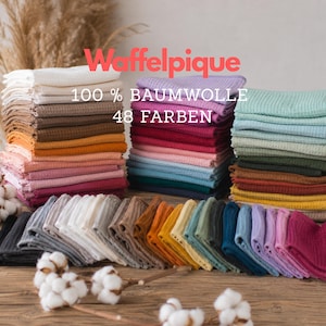Peut inclure: Piles de tissu gaufré plié dans une grande variété de couleurs, notamment blanc, beige, rose, rouge, bleu, vert et jaune. Le texte Waffelpique 100 % BAUMWOLLE 48 FARBEN est superposé sur l'image. Le tissu présente un motif en grille texturé.