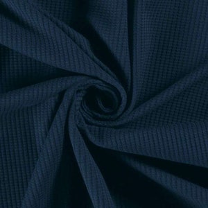 May include: Close-up of a dark blue waffle knit fabric. The fabric is soft and textured, with a subtle sheen.