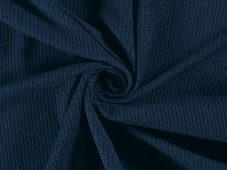 May include: Close-up of a dark blue waffle knit fabric. The fabric is soft and textured, with a subtle sheen.