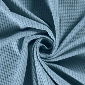 May include: A close-up of a blue waffle weave fabric. The fabric is soft and textured, with a subtle sheen.