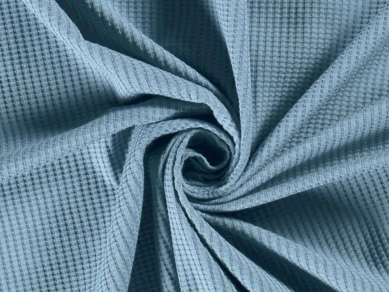 May include: A close-up of a blue waffle weave fabric. The fabric is soft and textured, with a subtle sheen.