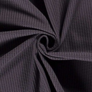 May include: A close-up of a dark purple waffle weave fabric. The fabric is folded and textured, showing the waffle pattern.