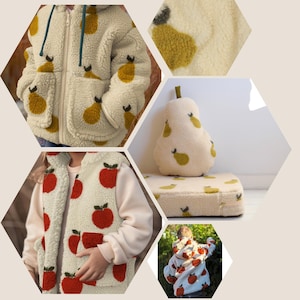 May include: Cream-coloured fleece jacket and vest with a fruit pattern. The jacket has a zip and pockets, while the vest features a sleeveless design. A pear-shaped cushion and a cushion with the same pattern are also shown.