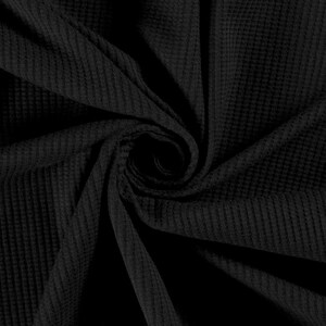 May include: Black waffle knit fabric with a textured surface. The fabric is folded and twisted, creating a swirling pattern.
