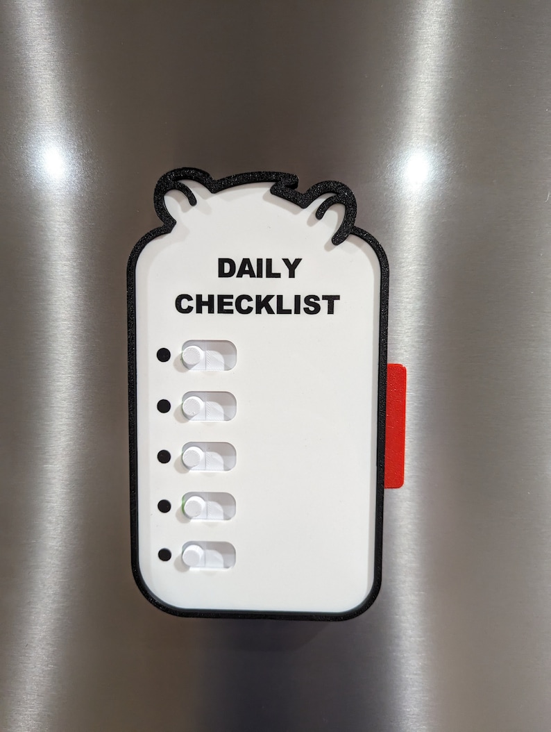 May include: White daily checklist with black border and text, "DAILY CHECKLIST." Features five toggle switches and a red tab. The checklist has a bear-shaped top and is mounted on a metallic surface.
