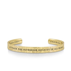 Puede incluir: Pulsera de brazalete de metal martillado de color dorado con la inscripción "Activar la Divinidad Soberana de Todos los Seres". La pulsera está grabada con "Sophia Code" y "Kaia Ra 2016".