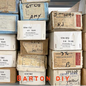 Op de afbeelding: Een verzameling vintage dozen, sommige met handgeschreven notities en productdetails. De dozen, in verschillende maten en kleuren, bevatten glazen kralen. De tekst "BARTON DIY" staat onderaan de afbeelding.
