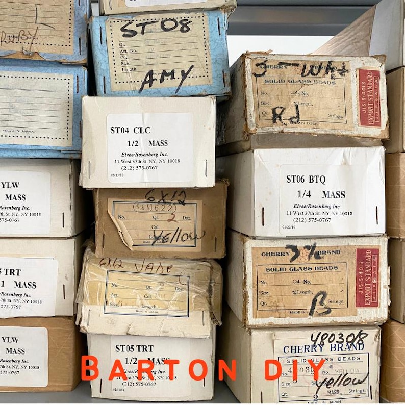 Op de afbeelding: Een verzameling vintage dozen, sommige met handgeschreven notities en productdetails. De dozen, in verschillende maten en kleuren, bevatten glazen kralen. De tekst "BARTON DIY" staat onderaan de afbeelding.
