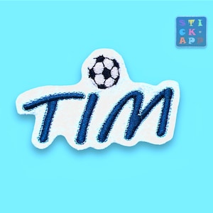 Könnte beinhalten: Gestickter Aufnäher mit dem Namen "TIM" in blauer Schrift, gekrönt von einem schwarz-weißen Fußball. Der Aufnäher befindet sich auf weißem Hintergrund mit hellblauem Hintergrund. Ein kleines quadratisches Patch mit "STICK APP" befindet sich oben rechts.