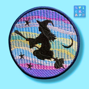 Könnte beinhalten: Ein runder gestickter Aufnäher mit der schwarzen Silhouette einer Hexe auf einem Besen vor einem Hintergrund aus horizontalen Streifen in Blau-, Lila- und Gelbtönen, akzentuiert durch kleine schwarze Sterne und eine Mondsichel.