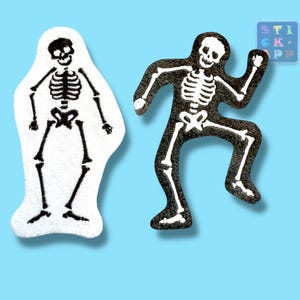 Könnte beinhalten: Zwei bestickte Aufnäher mit Skelettfiguren. Ein Aufnäher hat einen weißen Hintergrund mit einem aufrecht stehenden schwarzen Skelett. Der andere hat einen schwarzen Hintergrund mit einem weißen Skelett in einer dynamischen, tanzenden Pose.