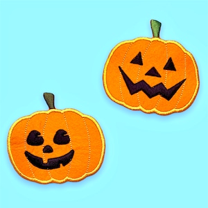 Könnte beinhalten: Zwei orangefarbene Filz-kürbis-Patches mit schwarzen Filz-Jack-o'-Lantern-Gesichtern. Die Kürbisse sind mit gelbem Garn gestickt.