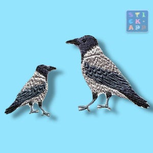 Könnte beinhalten: Zwei gestickte Aufnäher mit Nebelkrähen im Profil, dargestellt in Schwarz-, Grau- und Weißtönen. Die Vögel haben dunkle Köpfe, Schnäbel und Flügel mit hellgrauen Körpern. Ein kleines quadratisches Logo in der oberen rechten Ecke zeigt STICK APP.
