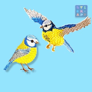 Könnte beinhalten: Zwei gestickte Aufnäher mit Blaumeisen, die gelbe Brust, blaue Flügel und weiße Gesichtsmarkierungen aufweisen. Ein Vogel ist sitzend dargestellt, während der andere im Flug mit ausgebreiteten Flügeln zu sehen ist. Ein kleines quadratisches Logo zeigt STICK APP.