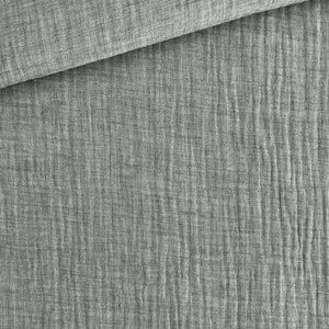 May include: Close-up of a gray fabric with a textured, crinkled appearance. The fabric is folded over, revealing a layered effect. The material has a soft, slightly wrinkled look, suggesting a lightweight textile.