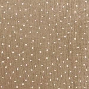 May include: Close-up of a tan fabric with a repeating pattern of white polka dots. The fabric has a slightly textured appearance, with the dots irregularly spaced across the surface. The overall effect is a simple, yet visually interesting design.