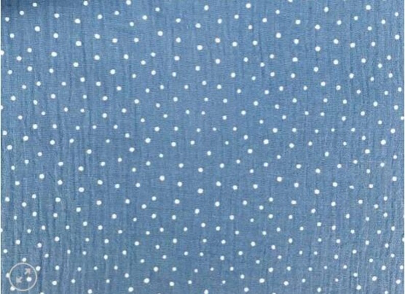 May include: Close-up of a blue fabric with a white polka dot pattern. The fabric has a slightly textured appearance, and the dots are evenly spaced across the surface. The overall effect is a classic and versatile design, suitable for various sewing projects.