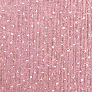 May include: A close-up of a dusty rose fabric with a crinkled texture. The fabric is dotted with evenly spaced white polka dots. The material appears to be a lightweight cotton or linen, suitable for clothing or home decor.