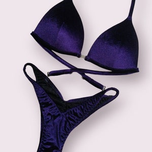 May include: A purple velvet bikini with a triangle top and a high-cut bottom.