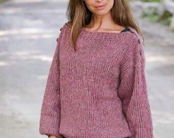 May include: A pink knitted sweater with a boat neck and long sleeves. The sweater has a textured knit and a subtle speckled pattern. The sweater is shown on a model wearing blue jeans.