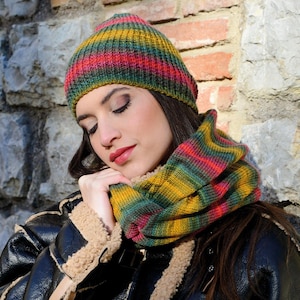 May include: A striped knitted hat and matching scarf in shades of green, yellow and pink. The hat is folded down and the scarf is wrapped around the neck.