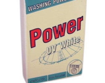 May include: A rectangular box of "Power" washing powder. The box is primarily beige with teal and red text. The text "WASHING POWDER" is at the top, with "Power" in large red letters. "UV White" is below, with a graphic of a washing machine.