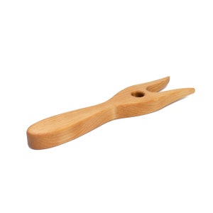Puede incluir: Una herramienta de madera con un mango y dos puntas, diseñada para recoger alimentos.