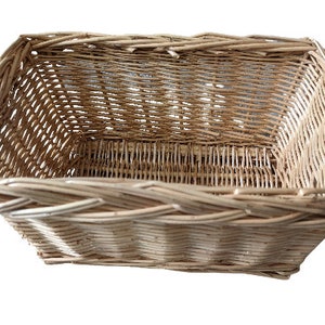 May include: A natural woven wicker basket with a rectangular shape. The basket is made of light brown wicker and has a woven pattern.