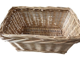 Puede incluir: Una cesta rectangular de mimbre tejido natural. La cesta está hecha de mimbre marrón claro y tiene un patrón tejido.