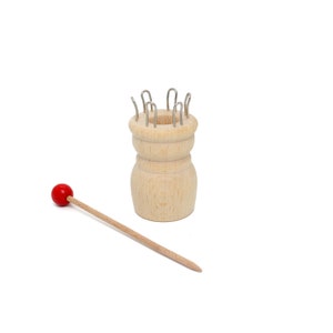 May include: A wooden knitting loom with metal hooks and a red wooden knitting needle.