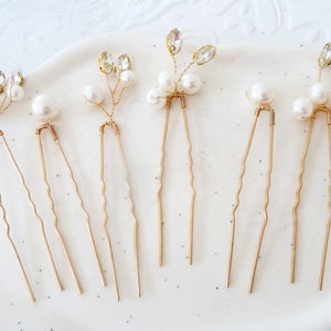 May include: Six gold hair pins with pearl and crystal accents. The pins have a wavy design and are perfect for adding a touch of sparkle to any hairstyle.