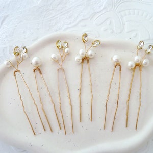 May include: Six gold hair pins with pearl and crystal accents. Each pin features a delicate branch design with small pearls and clear crystals.