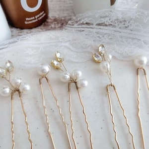 May include: Five gold hair clips with pearl and rhinestone accents. Each clip features a delicate floral design with small pearls and rhinestones.