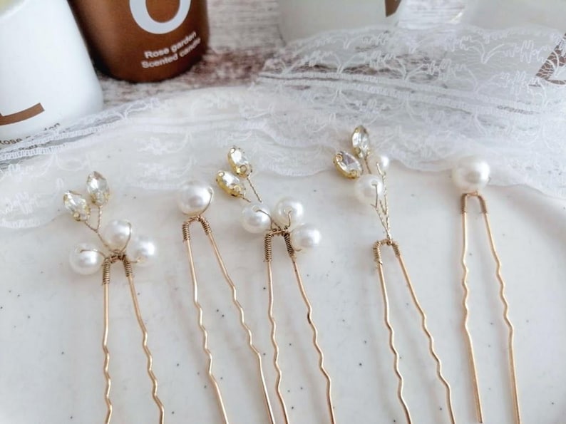 May include: Five gold hair clips with pearl and rhinestone accents. Each clip features a delicate floral design with small pearls and rhinestones.