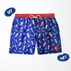 May include: Blue swim trunks with a lightning bolt pattern. The trunks have a red waistband and a drawstring. The text "Splash Apparel!" is printed on the right leg.