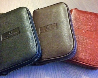 May include: Three leather zippered pouches in black, brown, and red. Each pouch has the text "The Leatherman Tool Group" embossed on the front.