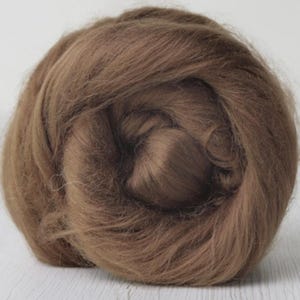 Könnte beinhalten: Nahaufnahme einer braunen Wollroving, fest zu einem kompakten Knäuel gewickelt. Die Fasern haben ein weiches, strukturiertes Aussehen und einen warmen, erdigen Ton. Die Wolle ist dicht gepackt und eignet sich für verschiedene Bastelprojekte.