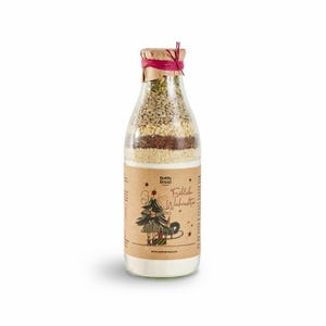 Könnte beinhalten: Eine Glasflasche gefüllt mit Zutaten für eine Weihnachtsbackmischung. Die Flasche ist in braunes Papier mit einem roten Band und einer festlichen Illustration eines Weihnachtsbaums und eines Mädchens, das einen Schlitten zieht, verpackt. Das Etikett lautet "Bottle Bread" und "Fröhliche Weihnachten".