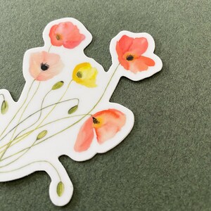 May include: A white sticker with a watercolor illustration of a bouquet of red, orange, and yellow flowers. The flowers are stylized and have a delicate, whimsical look.