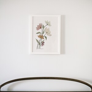 May include: A white framed print of a watercolor painting of a bouquet of pink, yellow, and white flowers on a white background.