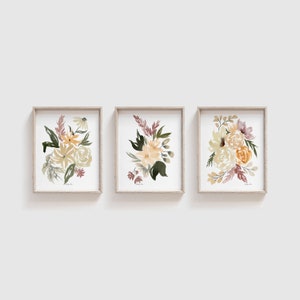 May include: Set of three framed watercolor prints featuring floral bouquets in shades of yellow, green, and pink. The bouquets are arranged in a modern style and are perfect for adding a touch of nature to any room.