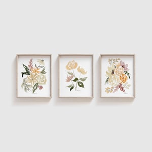 May include: Three framed watercolor paintings of floral bouquets in shades of yellow, orange, and brown. The paintings are in simple, modern frames.